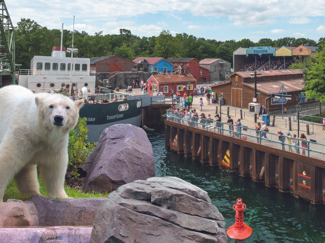 Erlebnis Zoo Hannover Eisbär im Zoo Hannover, vor Kulisse eines Hafenviertels mit bunten Gebäuden und einem Schiff.