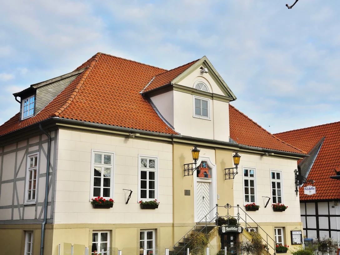 Ein altes Gebäude mit rotem Ziegeldach und weißen, symmetrischen Fassadenfenstern steht majestätisch.