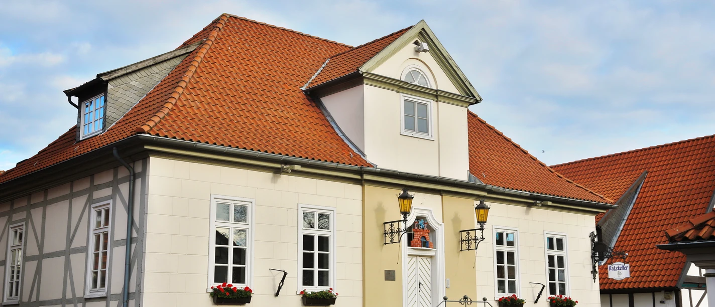 Ein altes Gebäude mit rotem Ziegeldach und weißen, symmetrischen Fassadenfenstern steht majestätisch.