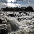 Wasserfall Neustadt a. Rbge. Tosendes Wasser fließt über dunkle Felsen in einer naturnahen Szenerie bei bewölktem Himmel.