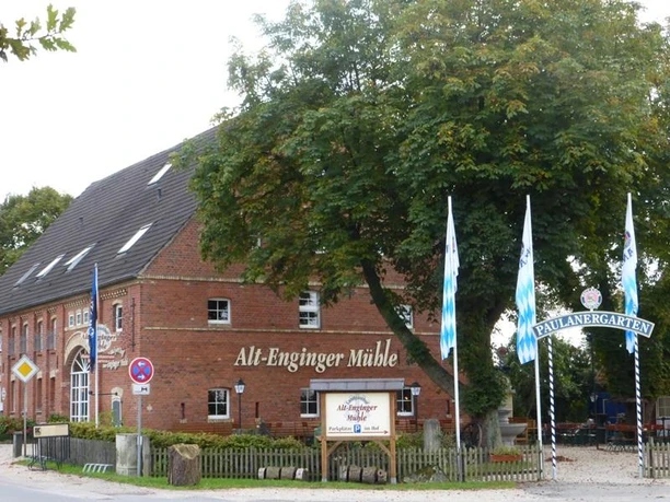 Historische Alt-Enginger-Mühle mit roter Ziegelfassade, großer Baum daneben, Paulanergarten.