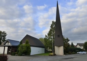 Evangelische Kirche Paderborn-Elsen Evangelische Kirche Paderborn-Elsen mit modernem spitzen Turm und umliegenden Bäumen an einem bewölkten Tag.