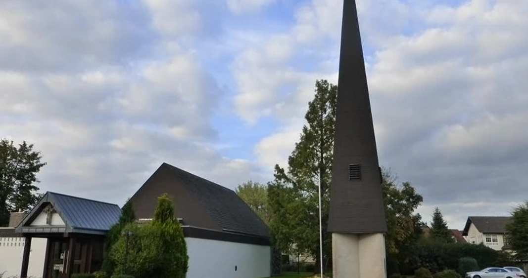 Evangelische Kirche Paderborn-Elsen Evangelische Kirche Paderborn-Elsen mit modernem spitzen Turm und umliegenden Bäumen an einem bewölkten Tag.