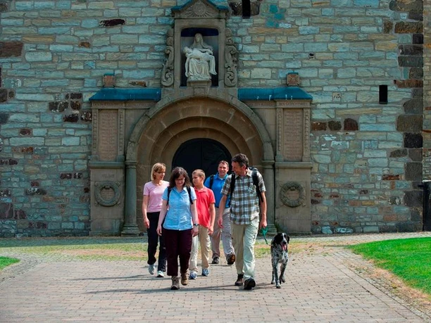 Mehrere Personen vor dem historischen Eingang der Pfarrkirche Paderborn-Neuenbeken.