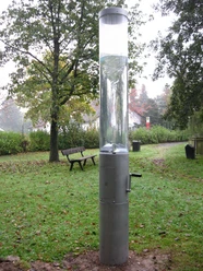 Wasserstrudel in Extertal-Laßbruch Transparenter Zylinder mit handbetriebenem Wasserstrudel, umgeben von grüner Parklandschaft im Extertal.