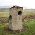 Summstein in Extertal-Laßbruch Großer, aufrecht stehender Steinblock mit runden Öffnungen in einer ländlichen Feldlandschaft.