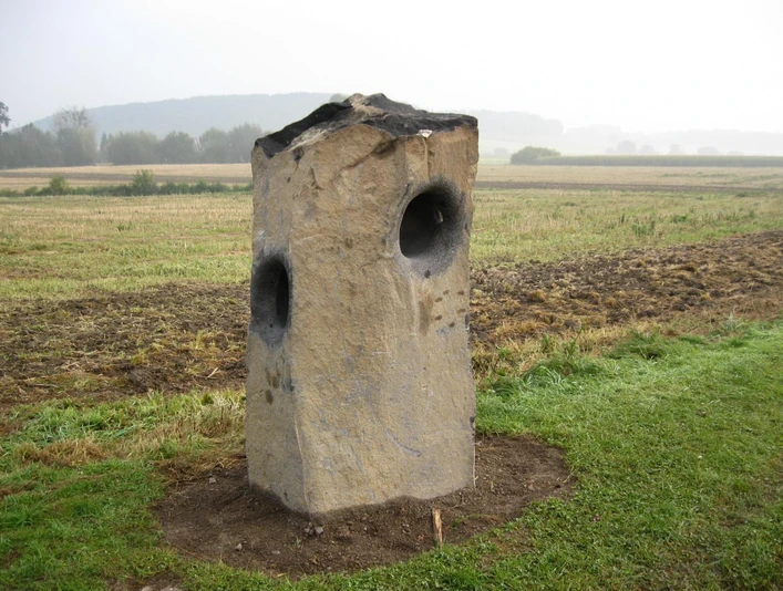 Summstein in Extertal-Laßbruch Großer, aufrecht stehender Steinblock mit runden Öffnungen in einer ländlichen Feldlandschaft.