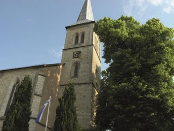 Kath. Pfarrkirche St. Margaretha Dahl mit markantem Turm aus Naturstein, flankiert von Bäumen.