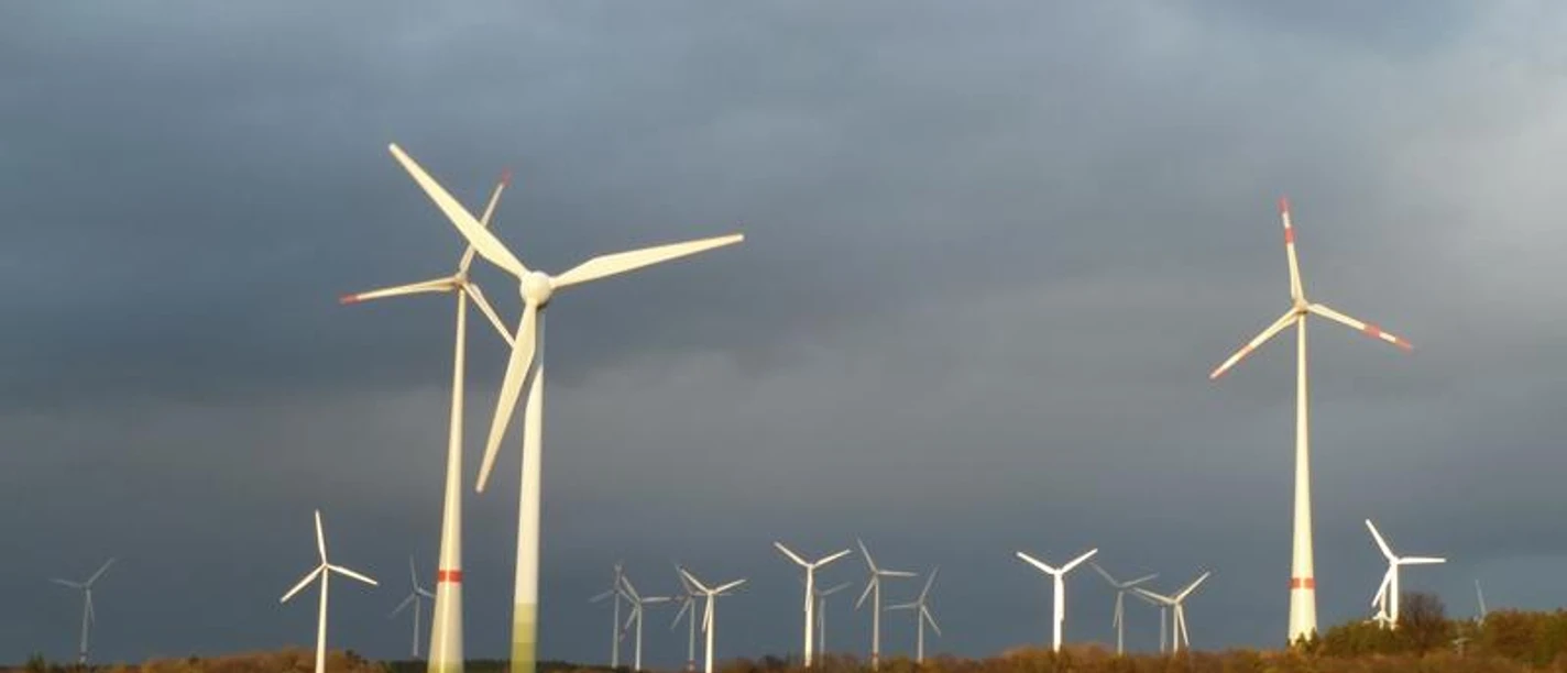 Windkraftanlagen auf dem Holterfeld Windkraftanlagen auf grüner Wiese unter bewölktem Himmel mit mehreren Windrädern im Hintergrund.
