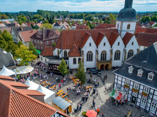 Seitenansicht der Pfarrkirche St. Johannes Baptist Luftaufnahme eines belebten Marktplatzes in einer historischen Stadt mit Kirchgebäude im Zentrum.