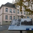 Erzbischöfliches Palais (Dalheimer Hof), Außenansicht Das historische Erzbischöfliche Palais mit heller Fassade und Infotafel im Vordergrund.