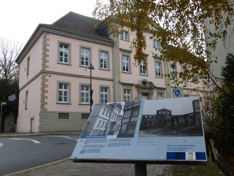Erzbischöfliches Palais (Dalheimer Hof), Außenansicht Das historische Erzbischöfliche Palais mit heller Fassade und Infotafel im Vordergrund.