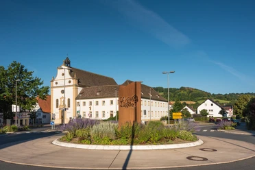Ehemaliges Franziskanerkloster in Lügde mit prächtiger Fassade, neoklassizistischem Stil umgeben von einer modernen Verkehrsinsel.