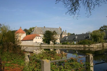 Historische Wasserschlossanlage mit Hauptgebäude, Nebengebäuden, umgeben von einem Wassergraben.