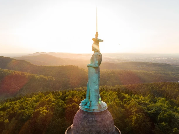 Das imposante Hermannsdenkmal ragt bei Sonnenuntergang über die bewaldete Landschaft des Teutoburger Waldes.