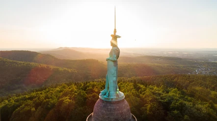 Hermannsdenkmal bei Sonnenuntergang Das imposante Hermannsdenkmal ragt bei Sonnenuntergang über die bewaldete Landschaft des Teutoburger Waldes.