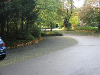 Der Parkplatz am Friedhof ist umgeben von herbstlichem Laub und bietet ausreichend Stellfläche.