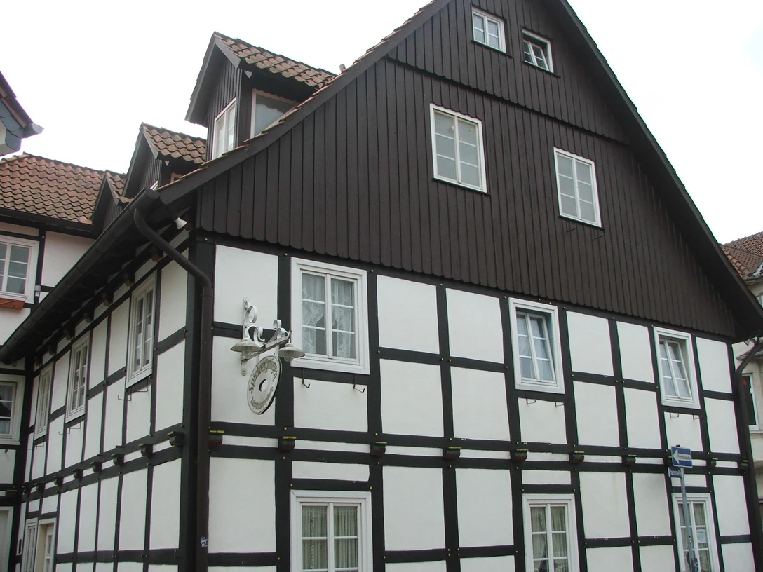Haus Trimmel Fachwerkhaus mit dunklem Holzgebälk und roten Dachziegeln, Fenster mit weißen Rahmen, historischer Stil.