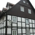 Haus Trimmel Fachwerkhaus mit dunklem Holzgebälk und roten Dachziegeln, Fenster mit weißen Rahmen, historischer Stil.