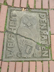 Steinboden mit einer stilisierten Eule und den Inschriften "WEISHEIT" und "DEN RATEN".