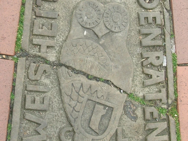 Bürgerstein Steinboden mit einer stilisierten Eule und den Inschriften "WEISHEIT" und "DEN RATEN".
