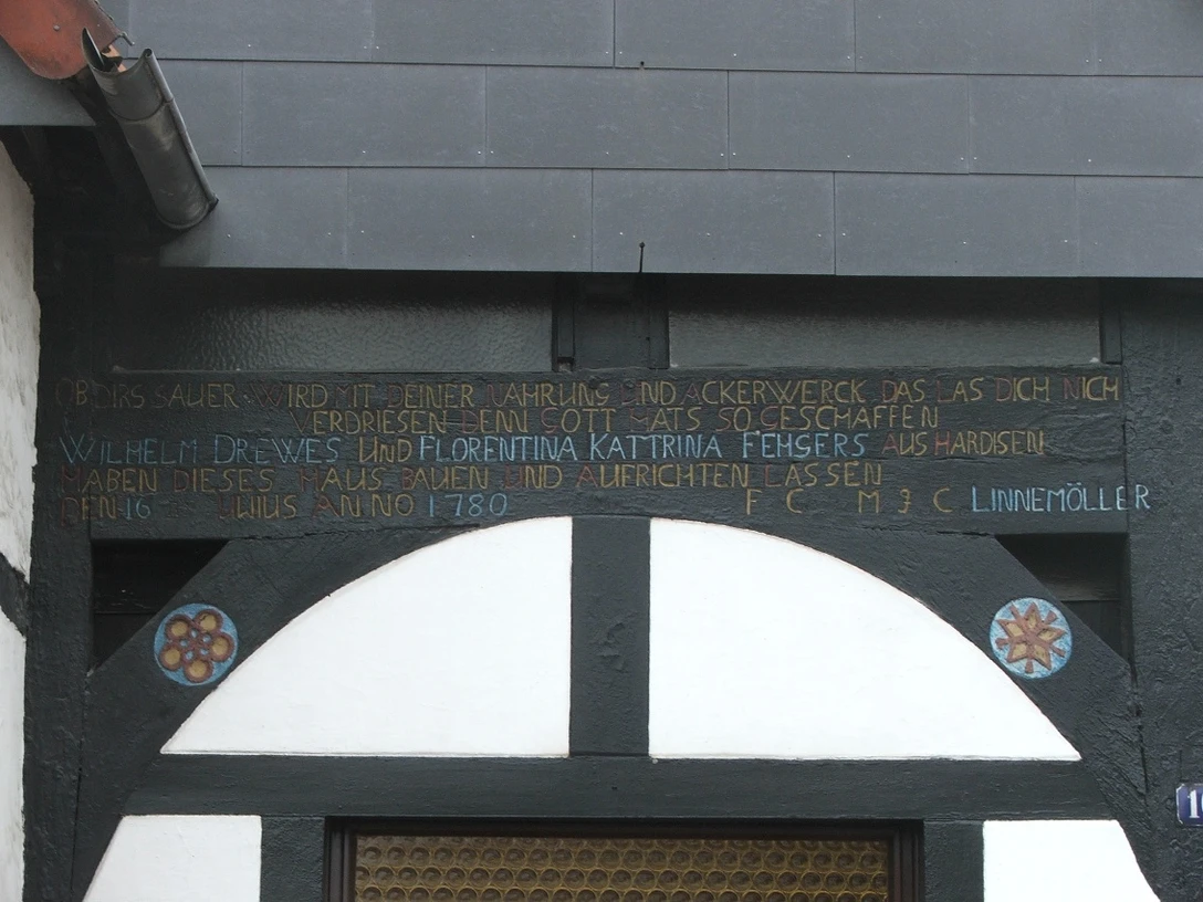 Fachwerkhaus Rhienstraße 16 Inschrift über der Tür eines Fachwerkhauses, datiert auf 1789, mit blumenverzierten Holzdetails.
