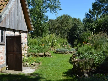 Burg Ravensberg - Bauerngarten Der Bauerngarten an Burg Ravensberg mit üppigen Beeten, Steinwegen und rustikalem Holzschuppen.