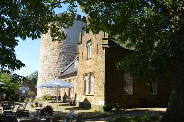 Burg Ravensberg Burg Ravensberg mit massiven Steinturm und restaurierter Fassade, umgeben von grünen Bäumen.