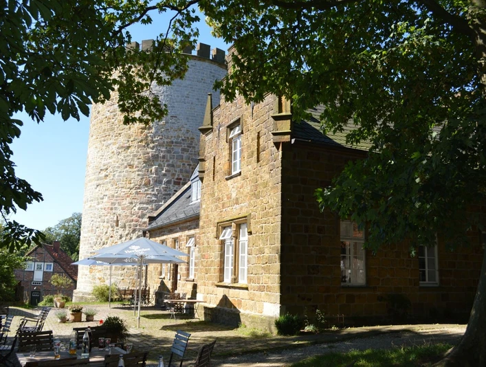 Burg Ravensberg Burg Ravensberg mit massiven Steinturm und restaurierter Fassade, umgeben von grünen Bäumen.