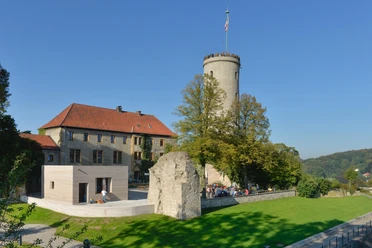 Sicht auf die mittelalterliche Sparrenburg in Bielefeld, umgeben von Bäumen bei klarem Himmel.