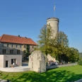 Sicht auf die mittelalterliche Sparrenburg in Bielefeld, umgeben von Bäumen bei klarem Himmel.