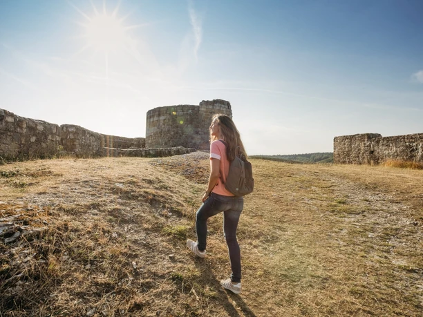 Ruine Falkenburg Eine Frau mit Rucksack geht bei sonnigem Wetter auf einen Hügel zur Ruine Falkenburg.