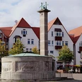 Paulinenquelle Historischer Brunnen auf einem Platz mit umliegenden Fachwerkhäusern vor bewölktem Himmel.