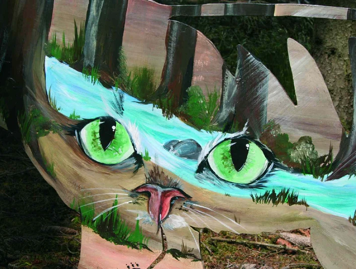 Katzen-Augen-Blicke Ein Gemälde einer Katze mit auffällig grünen Augen, umgeben von Naturmotiven, auf Holzhintergrund.