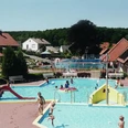 Waldschwimmbad Preußisch Oldendorf Kinderbecken mit Rutsche und Wasserspielen vor einem Waldschwimmbad an einem sonnigen Tag.