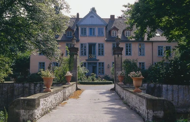 Gutshof Engershausen Historisches Herrenhaus mit gelber Fassade, symmetrischen Fenstern und Natursteinsäulen vor dem Eingang.