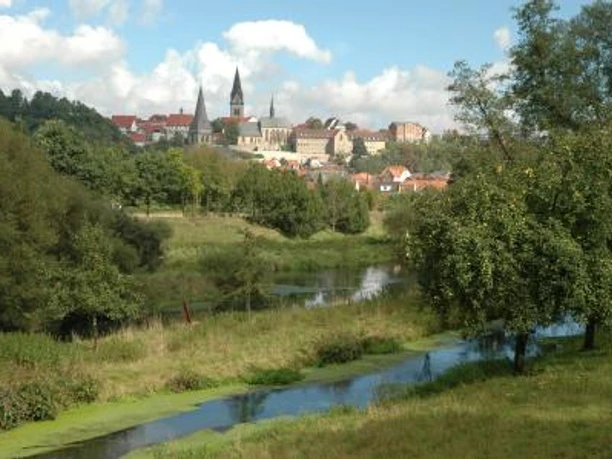 Blick auf die historische Stadt Warburg mit markanten Kirchtürmen und umgeben von grüner Natur.