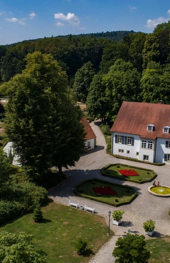 Historisches Herrenhaus im Kurpark Bad Holzhausen, umgeben von gepflegten Gärten und Waldkulisse.