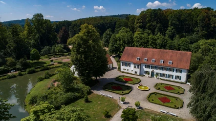 Kurpark Bad Holzhausen Historisches Herrenhaus im Kurpark Bad Holzhausen, umgeben von gepflegten Gärten und Waldkulisse.