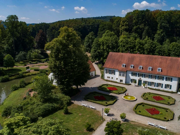 Kurpark Bad Holzhausen Historisches Herrenhaus im Kurpark Bad Holzhausen, umgeben von gepflegten Gärten und Waldkulisse.