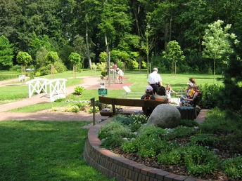 Rastplatz am Garten der Generationen Ruhiger Rastplatz im Grünen, umgeben von Bäumen und Pflanzen, mit Sitzgelegenheiten für Besucher.