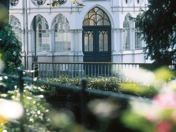 Liborius-Trinkhalle Bad Lippspringe Historisches Gebäude mit verzierten Fenstern, umgeben von üppigem Grün und einem plätschernden Bach.