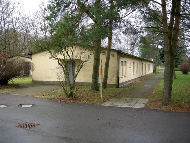Langgestrecktes, flaches Gebäude der Dokumentationsstätte Stalag 326 inmitten einer bewaldeten Umgebung.