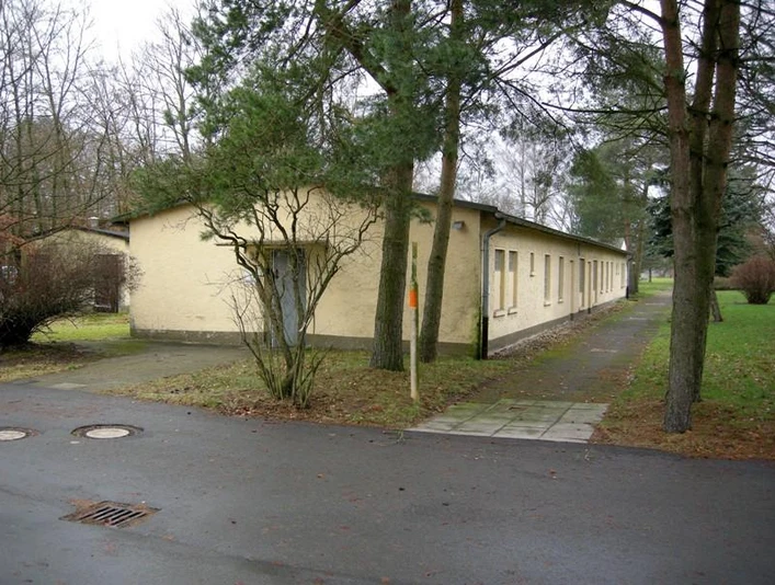 Langgestrecktes, flaches Gebäude der Dokumentationsstätte Stalag 326 inmitten einer bewaldeten Umgebung.