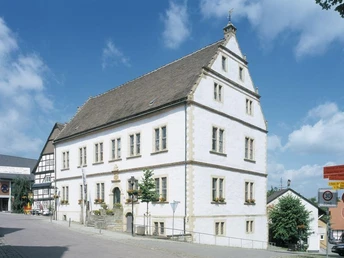 Historisches Rathaus Historisches Gebäude mit Schieferdach und weißen Wänden, umgeben von modernen Straßenelementen.