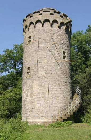 Holsterturm Wahrzeichen der Stadt Steinerner Turm inmitten grüner Vegetation, mit Wendeltreppe und markanten Zinnen am oberen Rand.