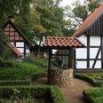 Traditionelles Fachwerkhaus mit gepflegtem Garten und einem alten Ziehbrunnen im Vordergrund.