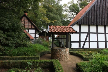Heimatmuseum Versmold Traditionelles Fachwerkhaus mit gepflegtem Garten und einem alten Ziehbrunnen im Vordergrund.