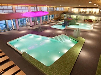 ThermenLandschaft mit IntensivsoleBecken, RegenWolke, SprudelBecken, Heiß-KaltBecken Moderne Innenansicht einer Therme mit beleuchteten Solebecken und entspannenden Liegen.