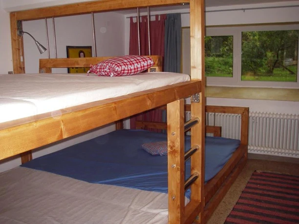 Zweckmäßige Schlafräume mit Stockbetten, Fenster zeigt den Blick auf grünes Außenambiente.